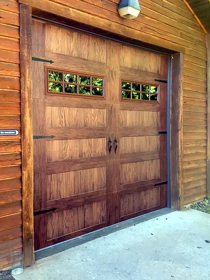 Wood-look carriage house garage door with windows and black strap hinges