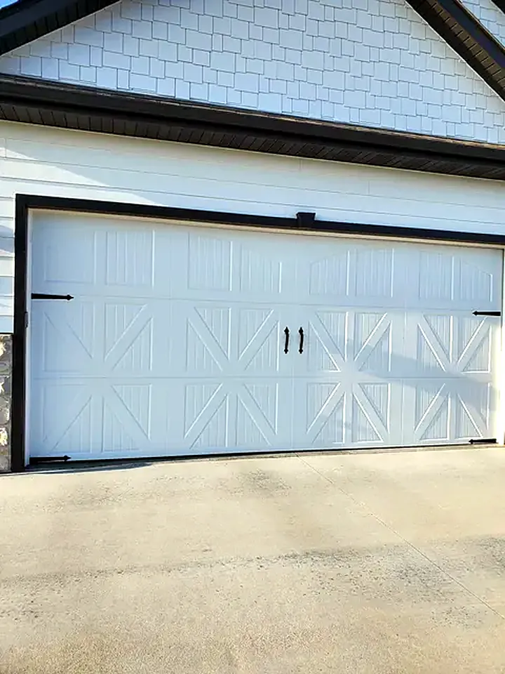 White carriage-style garage door with X-brace panels and black hardware